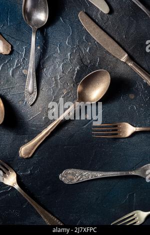 Posate piatto. Cucchiai, forchette e coltelli, vari utensili da tavola, sparati dall'alto su sfondo nero Foto Stock