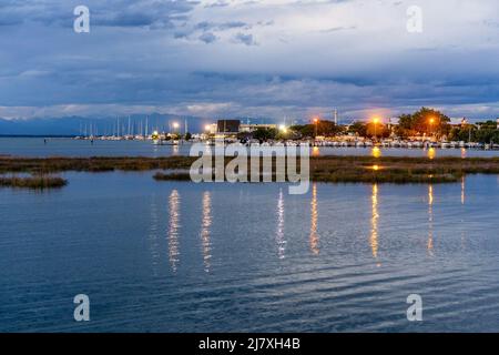 Bellissimo e tranquillo tramonto sul piccolo porto marino con le nuvole blu e le luci si riflettono nell'acqua Foto Stock