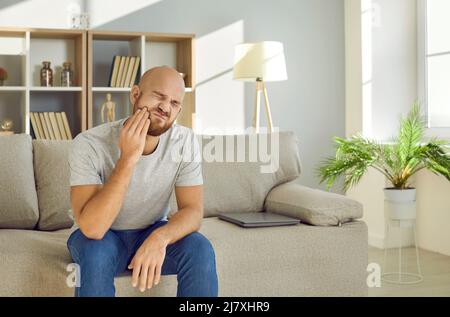 Il giovane con espressione dolorosa tiene la sua guancia affetta da gravi mal di denti. Foto Stock