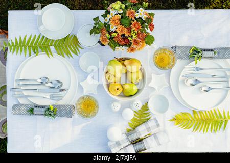 Tavolo per le vacanze estive. Elegante tavolo con piatti bianchi su tovaglia di lino bianco. Frutta, bevande in bicchieri di cristallo. Tavolo impostato per out Foto Stock