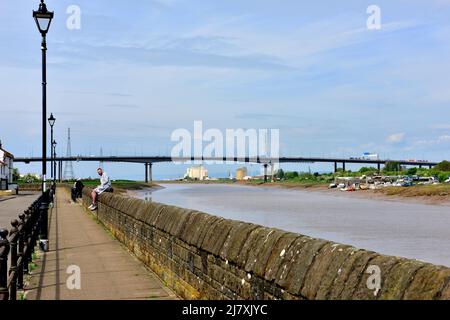 Marea parete difensiva lungo l'estuario del fiume Avon al villaggio di pillola, North Somerset, Inghilterra. Ponte di Avonmouth sullo sfondo Foto Stock