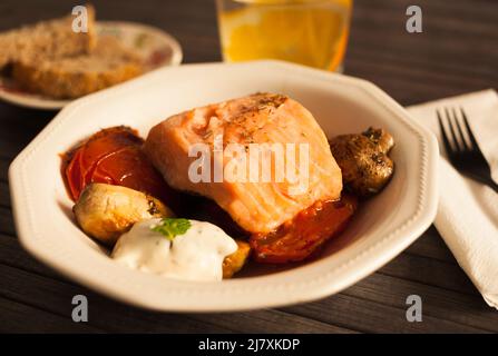 filetto di trota di mare al vapore servito su funghi fritti con pomodori in un recipiente bianco Foto Stock