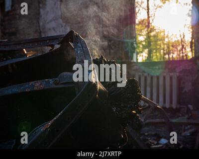 Regione di Kharkiv, Kharkov, Skovorodinovka, Skovorodinivka, Ucraina - 05.07.2022: Rovine bruciate fumare distrutto palo di metallo che brucia le attrezzature militari in Foto Stock