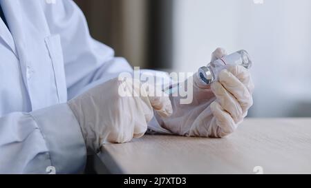 Medico donna irriconoscibile farmacista che indossa guanti di lattice che tengono la siringa e il flacone di covid 19 liquido vaccino rimedio cura farmaco preparazione per Foto Stock