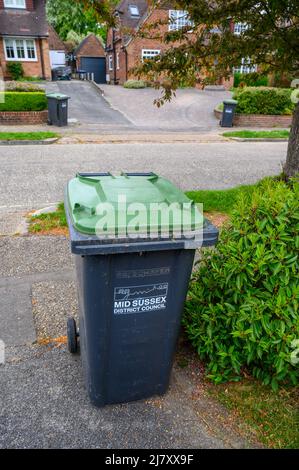 Bidoni verdi in strada residenziale pronti per la raccolta. Foto Stock