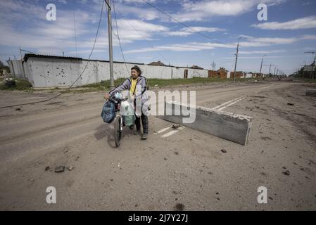 Kharkiv, Ucraina. 11th maggio 2022. Una donna cammina la sua bicicletta vicino a un muro in vaso con shrapnel da russo shelling nelle parti settentrionali di Kharkiv, Ucraina, mercoledì 11 maggio 2022. Martedì gli Stati Uniti e i suoi alleati europei hanno accusato la Russia di un attacco informatico lanciato un'ora prima dell'invasione di febbraio del Cremlino dell'Ucraina che ha preso di mira una società di comunicazione statunitense che opera a Kiev, causando danni in tutto il continente. Foto di Ken Cedeno/UPI Credit: UPI/Alamy Live News Foto Stock