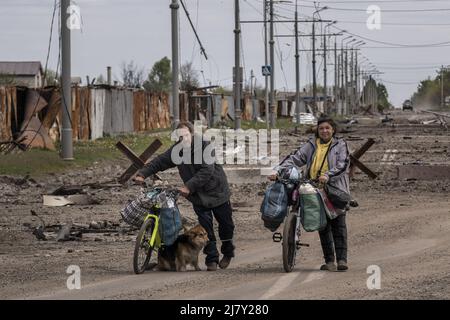 Kharkiv, Ucraina. 11th maggio 2022. Due persone camminano le loro biciclette lungo una strada cosparsa di detriti provenienti dall'abbattimento russo nelle parti settentrionali di Kharkiv, Ucraina, mercoledì 11 maggio 2022. Martedì gli Stati Uniti e i suoi alleati europei hanno accusato la Russia di un attacco informatico lanciato un'ora prima dell'invasione di febbraio del Cremlino dell'Ucraina che ha preso di mira una società di comunicazione statunitense che opera a Kiev, causando danni in tutto il continente. Foto di Ken Cedeno/UPI Credit: UPI/Alamy Live News Foto Stock