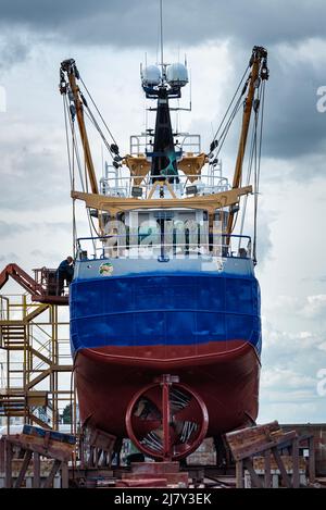 Nave o nave grande con elica visibile riparata sul molo all'esterno dell'acqua. Pescherecci da traino ancorati con problemi meccanici in un porto da fissare Foto Stock