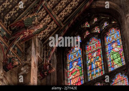 I colorati angeli di legno guardano in basso dal soffitto dipinto del transetto Nord della Cattedrale di Ely Foto Stock