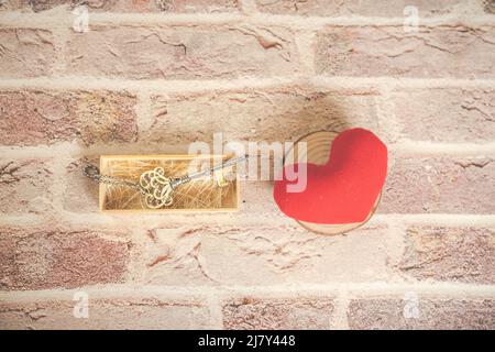 Chiave casa in bronzo e rosso tessuto paese cuore vecchio legno, San Valentino, immobiliare e concetto di fondo casa con legno dipinto copia spazio. Foto Stock