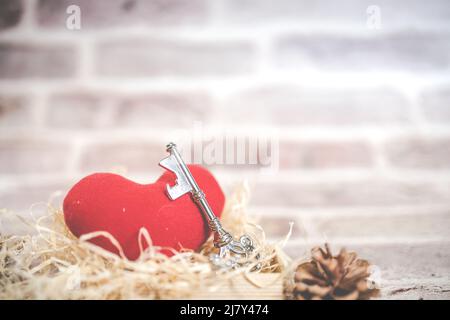 Chiave casa in bronzo e rosso tessuto paese cuore vecchio legno, San Valentino, immobiliare e concetto di fondo casa con legno dipinto copia spazio. Foto Stock