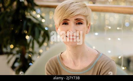 Testa ripresa mezza età caucasica bionda donna con acconciatura corta interno sorriso bianco denti guarda fotocamera si sente sicuro e felice 40s femmina Foto Stock