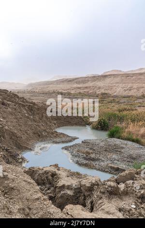 Buca piena di acque turchesi, vicino alla costa del Mar Morto. Foro formato quando il sale sotterraneo è dissolto da intrusione di acqua dolce, dovuto la caduta continua del livello del mare. . Foto di alta qualità Foto Stock