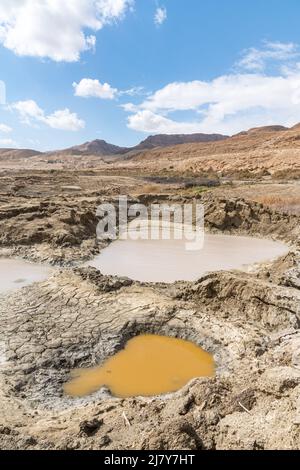 Buca piena di acque turchesi, vicino alla costa del Mar Morto. Foro formato quando il sale sotterraneo è dissolto da intrusione di acqua dolce, dovuto la caduta continua del livello del mare. . Foto di alta qualità Foto Stock