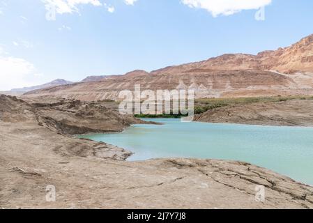 Buca piena di acque turchesi, vicino alla costa del Mar Morto. Foro formato quando il sale sotterraneo è dissolto da intrusione di acqua dolce, dovuto la caduta continua del livello del mare. . Foto di alta qualità Foto Stock