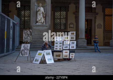 Un ritratto di strada attende il suo prossimo cliente nel cortile della Galleria degli Uffizi di Firenze Foto Stock