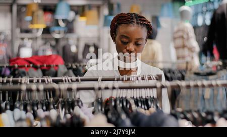 Da solo felice African American ragazza millennial donna acquirente cliente acquirente in piedi in negozio di abbigliamento centro commerciale scegliendo abiti alla moda merci femmina Foto Stock