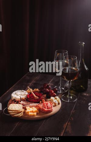 Antipasto di vino. Salsiccia e formaggio tagliati con frutta, biscotti e salsa con due bicchieri di porto bianco e una bottiglia. Foto Stock