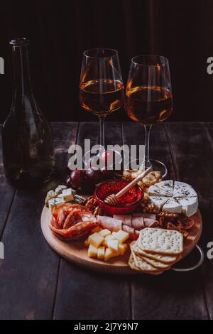 Salsiccia e formaggio tagliati con frutta, biscotti e salsa con due bicchieri di porto bianco e una bottiglia. Antipasto di vino, salumi e piatto di formaggi Foto Stock