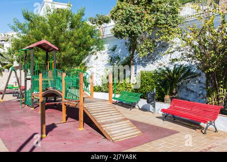 Parco giochi vuoto con altalene, una sala giochi e panchine colorate Foto Stock