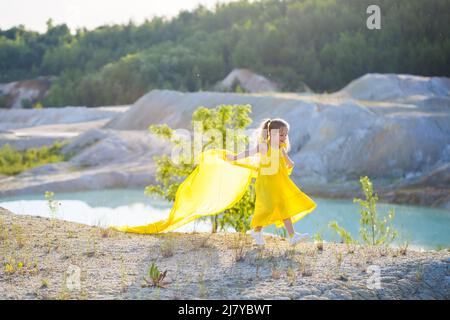 Ragazza Ucraina di 7 anni, è una patriota di Ucraina, vestita con un abito giallo contro un cielo blu. Cielo blu. Giorno di sole. Bambini ucraini gratis. CHIL Foto Stock