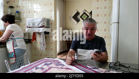 Felice uomo anziano che celebra le notizie sul cellulare. Senior sceglie lo smartphone con gioia Foto Stock