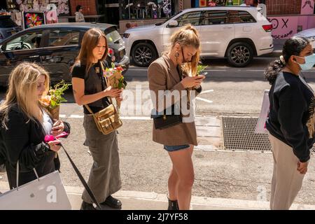 Guidati dai social media e dal passaparola, centinaia di persone, alcuni con mazzi che hanno ricevuto da un'attivazione del marchio Coach prima, attendere on line per ricevere una tazza di caffè gratuita da Burberry, a Soho a New York Sabato, 30 aprile 2022. (© Richard B. Levine) Foto Stock