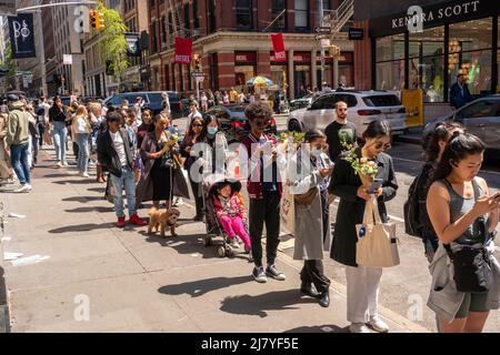 Guidati dai social media e dal passaparola, centinaia di persone, alcuni con mazzi che hanno ricevuto da un'attivazione del marchio Coach prima, attendere on line per ricevere una tazza di caffè gratuita da Burberry, a Soho a New York Sabato, 30 aprile 2022. (© Richard B. Levine) Foto Stock