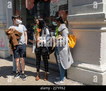 Le donne con i loro fiori ambiti dopo l'attesa in linea per ricevere un bouquet libero da Coach, a Soho a New York il sabato 30 aprile 2022. L'attivazione del marchio, alimentata dai social media, è stata una promozione per la collaborazione di Coach e ShopRunner per fornire la spedizione gratuita. (© Richard B. Levine) Foto Stock