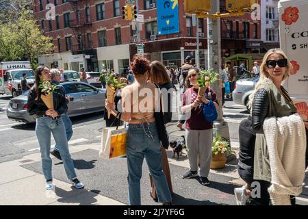 Le donne con i loro fiori ambiti dopo l'attesa in linea per ricevere un bouquet libero da Coach, a Soho a New York il sabato 30 aprile 2022. L'attivazione del marchio, alimentata dai social media, è stata una promozione per la collaborazione di Coach e ShopRunner per fornire la spedizione gratuita. (© Richard B. Levine) Foto Stock