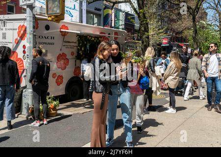 Le donne con i loro fiori ambiti dopo l'attesa in linea per ricevere un bouquet libero da Coach, a Soho a New York il sabato 30 aprile 2022. L'attivazione del marchio, alimentata dai social media, è stata una promozione per la collaborazione di Coach e ShopRunner per fornire la spedizione gratuita. (© Richard B. Levine) Foto Stock