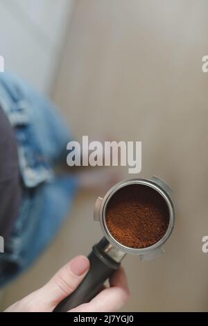 Il barista prepara il caffè e tiene in mano il portafiltro da una macchina da caffè. Primo piano. Foto di alta qualità Foto Stock