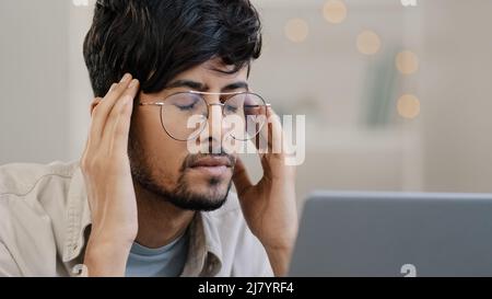 Primo piano arabo uomo d'affari studente maschio bordati capo con occhiali ragazzo lavora con problemi notebook soffre di mal di testa massaggi sensazione Foto Stock