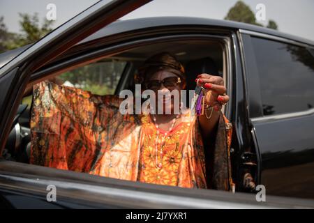una signora africana seduta nella sua auto tiene le chiavi in mano, concetto di servizi di noleggio auto Foto Stock