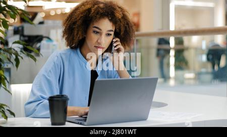 African american occupato business donna freelancer ragazza manager capo capo donna lavoratore parlare dal telefono cellulare rispondere chiamata scrive note di lavoro Foto Stock