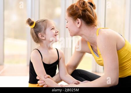 Mamma giovane in forma che guarda amorevolmente sua figlia Foto Stock