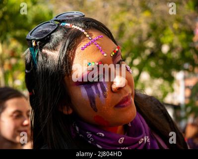Medellin, Antioquia, Colombia - Marzo 8 2022: Una giovane donna con pittura facciale applica Makeup ad un'altra donna prima della marcia femminista della Giornata della Donna Foto Stock