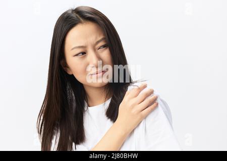 Soffrendo di nevralgia dopo aver dormito in posizione errata abbronzato bella giovane donna asiatica toccando dolorosa spalla isolata su sfondo bianco Foto Stock