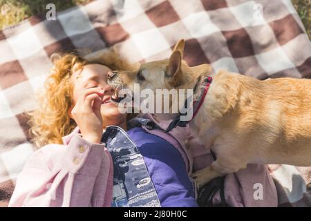 bella ragazza bionda che gioca con il suo cane sulla copertura nel parco medio closeup outdoor pet concetto. Foto di alta qualità Foto Stock