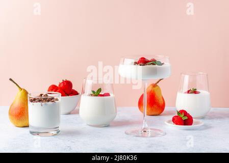yogurt con lamponi e granola in un bicchiere e bicchieri su un Foto Stock