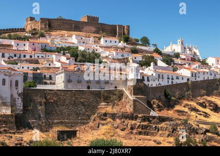 Vista di parte del villaggio di Mértola in Portogallo, evidenziando il suo castello e la chiesa, in una giornata di sole in estate. Foto Stock