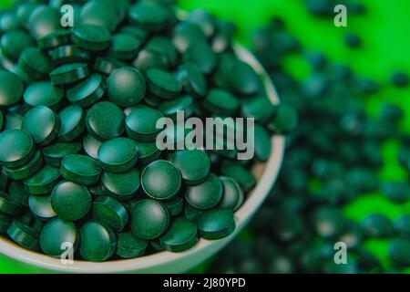 Spirulina compresse su sfondo verde. Spirulina compresse alghe. Vitamine e supplementi dietetici.Super cibo .Food Foto Stock