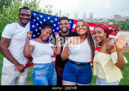 Gruppo di ragazze e ragazzi sorridenti con la bandiera americana in primavera parco autunno sera imparare inglese scambio studenti Foto Stock