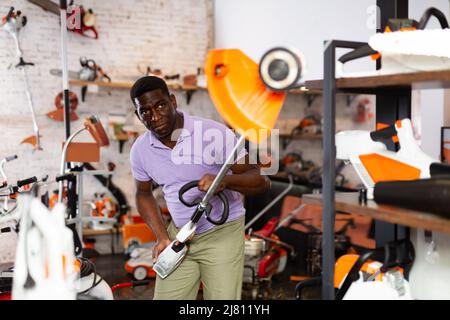 Uomo che seleziona nuovo Strimmer nel negozio di attrezzi di giardinaggio Foto Stock