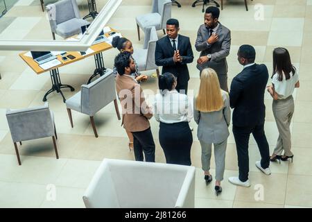 Persona d'affari asiatica in multirazziale. Diversità uomini d'affari formano da diverse razze, indiana, malese, indonesiana, cinese e africana in camera moderna Foto Stock