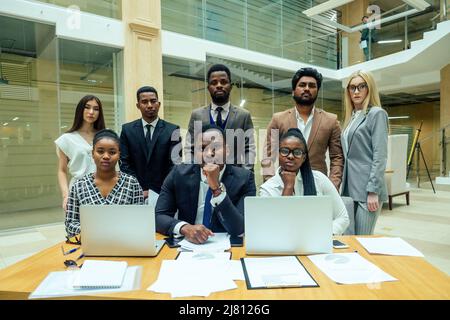 Persona d'affari asiatica in multirazziale. Diversità uomini d'affari formano da diverse razze, indiana, malese, indonesiana, cinese e africana in camera moderna Foto Stock