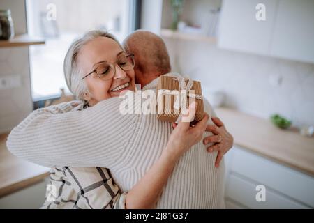 Donna anziana felice che ottiene presente da suo marito. Foto Stock
