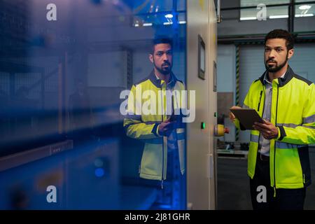 Giovane operaio industriale che lavora macchine cnc nell'industria della lavorazione dei metalli Foto Stock