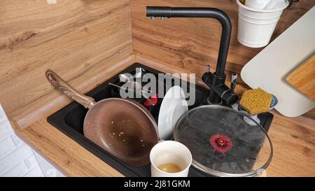 Un mucchio di piatti sporchi dopo aver cucinato la colazione si trova nel lavandino Foto Stock