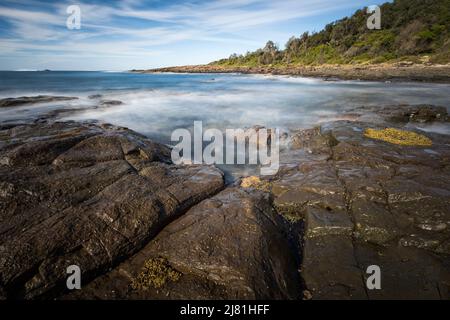 lunga esposizione di acqua e rocce lungo la costa a shellharbour in nsw Foto Stock